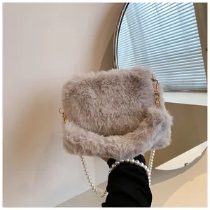 Detail of soft faux fur crossbody bag with elegant pearl chain and gold metal clasp