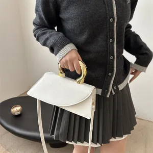 Elegant white crossbody bag with bold gold metal handle and detachable shoulder strap