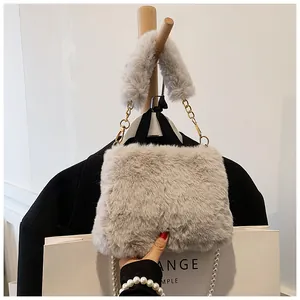 Detail of plush faux fur handbag with golden chain strap and soft textured handle