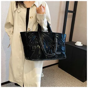 Détail du sac cabas matelassé noir brillant avec étiquette Fashion porté sur un trench