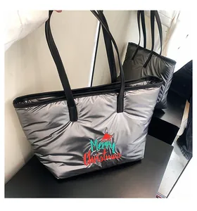 Gros plan sur un sac cabas argenté matelassé avec broderie Merry Christmas et bonnet rouge
