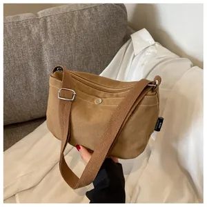 Detail of khaki canvas crossbody bag with silver metal snap pocket and adjustable strap