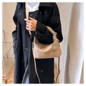 Détail du tissage du sac beige avec pendentif rond en cuir et chaîne métallique chic