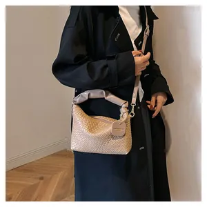 Détail du sac à bandoulière tissé beige avec poignée plissée et étiquette de mode