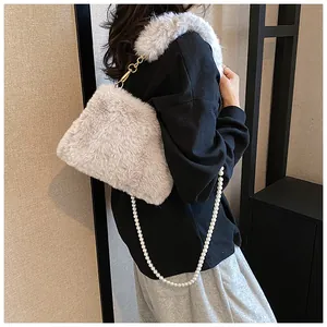 Macro shot of grey faux fur shoulder bag featuring pearl chain and gold metal buckle