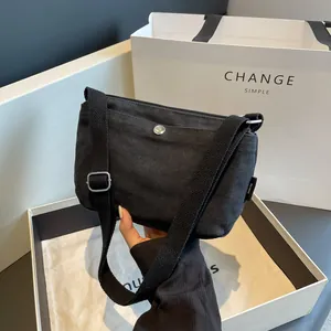 Minimalist black canvas crossbody bag with metal snap button and adjustable shoulder strap