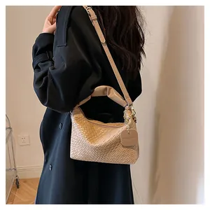 Détail du sac cabas beige tissé main avec texture cuir et finitions dorées sur modèle