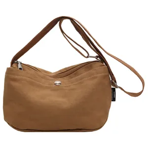 Minimalist brown canvas crossbody bag with adjustable strap and front pocket detail