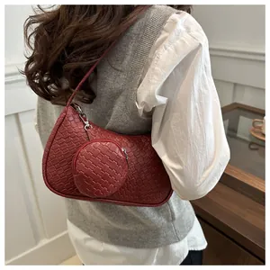 Detail of woven burgundy underarm bag featuring a small round coin purse and metal zipper