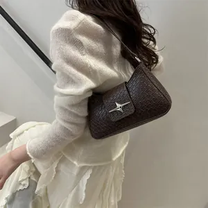 Brown crocodile pattern underarm bag with silver star buckle worn by a model