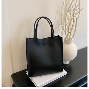 Minimalist black leather handbag on vintage books with decorative white vase
