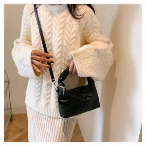 Détail d'un sac seau noir en cuir tressé à la main avec une étiquette logo dorée