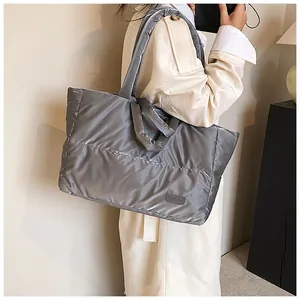 Détail d'un sac cabas matelassé gris avec étiquette fashion et bandoulière rembourrée