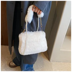 Detail of white faux fur handbag featuring elegant pearl handle and gold chain strap