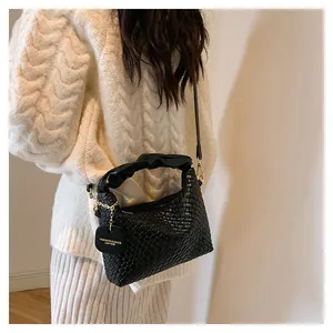 Détail du sac à main tissé noir avec ferrures dorées et bandoulière porté par un mannequin