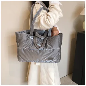 Sac fourre-tout matelassé argenté avec doubles poignées porté par un mannequin en intérieur