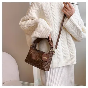 Détail d'un sac à main marron foncé tissé à la main avec pendentif mode et boucles dorées