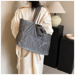 Vue détaillée d'un grand sac cabas matelassé gris porté par un mannequin en trench beige