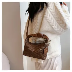Détail du sac à bandoulière tressé marron foncé avec texture et étiquette en cuir mode