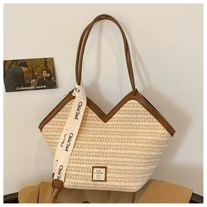 Detailed close-up of woven tote bag featuring a V-shaped opening and brown leather handles