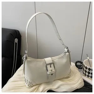 Dettaglio della borsa tote bianco crema con borchie argentate e fibbia in metallo su tessuto