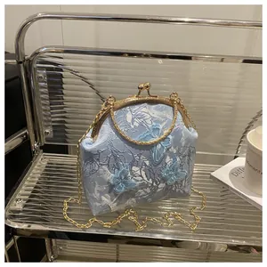 Detailed shot of light blue lace bag with 3D butterfly appliques and gold kiss-lock frame
