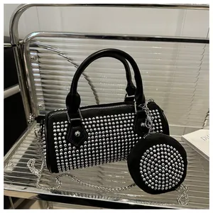 Detail view of black studded cylinder bag set with silver chain and coin purse charm