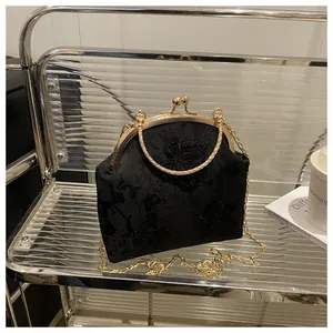 Detail of black lace handbag with butterfly embroidery and golden metal hardware