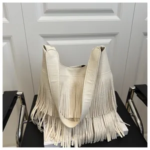 Detail der beigen Hobo-Tasche mit langen Fransen und Litschi-Struktur auf Ledersessel