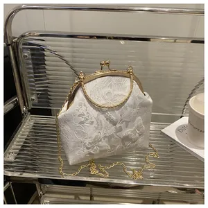 Detailed macro view of white lace embroidery with 3D butterfly appliqué on a metal frame bag