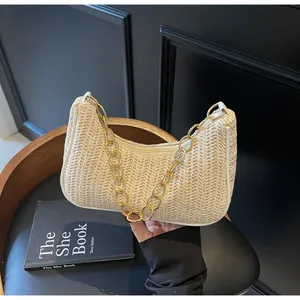 Detail der gewebten Strohtasche mit weißem Lederbesatz und goldener Kette