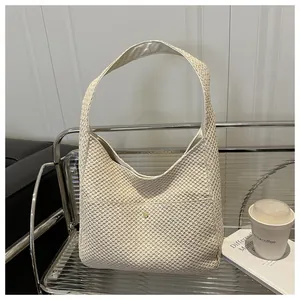 Dettaglio di una borsa hobo beige intrecciata con tracolla larga e pratica tasca frontale