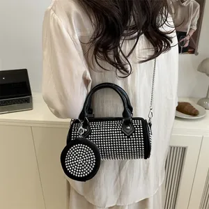 Fashionable black cylinder bag with silver studs and chain strap in a lifestyle setting