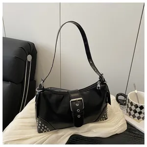 Dettaglio borsa punk con borchie argentate e fibbia su pelle nera lucida vintage