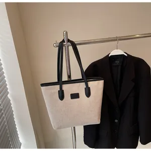 Close-up of canvas tote bag with black leather trim hanging on a metal hanger