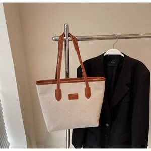 Detail view of large canvas tote bag with brown leather trim and shoulder straps