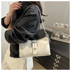 Dettaglio della borsa tote vintage color crema con borchie, fibbia argento e giacca nera