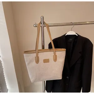 Detail of minimalist cream canvas tote bag with brown leather straps hanging on a hanger
