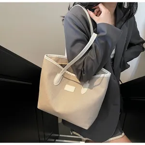 Khaki canvas tote bag with white faux leather handles shown on shoulder by model
