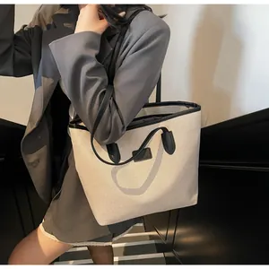 Close-up of minimalist cream canvas tote bag with black leather handles and dual straps