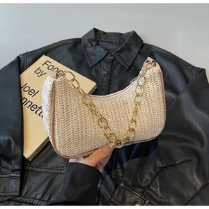 Detail der gewebten Halbmond-Strandtasche mit beiger Strohtextur und klobiger Goldkette