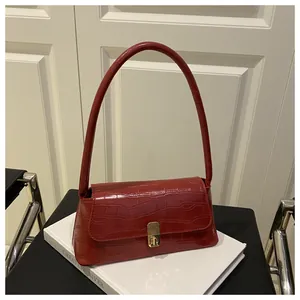 Détails de la texture crocodile rouge foncé et du fermoir métallique doré de ce sac chic