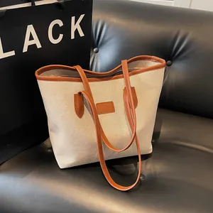 Minimalist canvas tote bag with brown leather trim and handles for daily commuting