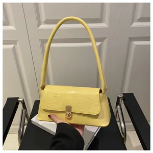 Vue détaillée de la texture crocodile jaune et du fermoir métallique du sac à main