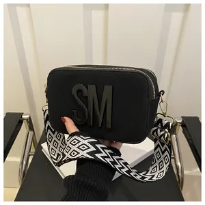 Detail of black camera bag with SM logo and geometric pattern wide shoulder strap