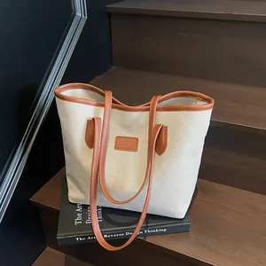 Minimalist canvas tote bag with brown leather trim displayed on a wooden staircase
