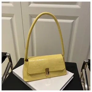 Détail du sac sous l'aisselle jaune clair à motif crocodile avec boucle en métal doré