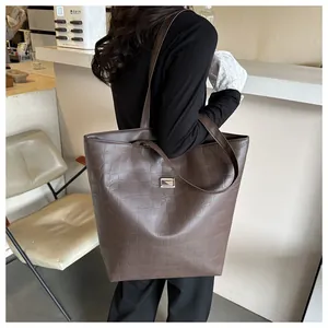 Detail of dark brown tote bag with crocodile texture and elegant metal buckle in a cafe