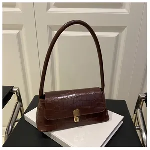 Détail du sac sous l'aisselle marron foncé à motif crocodile et boucle dorée