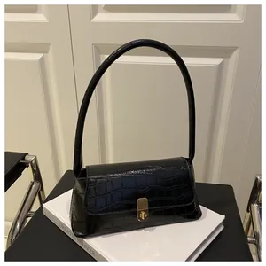 Détail d'un sac sous les aisselles en cuir noir crocodile avec boucle dorée